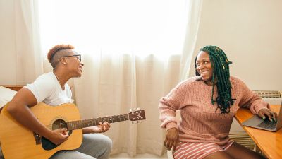 Happy lesbian couple playing guitar.